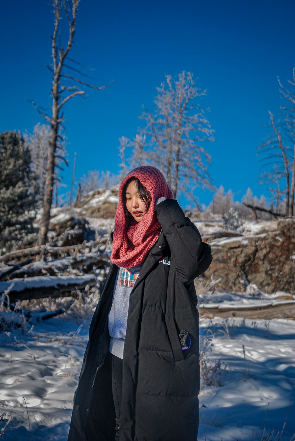 a woman standing in the snow wearing a coat and scarf