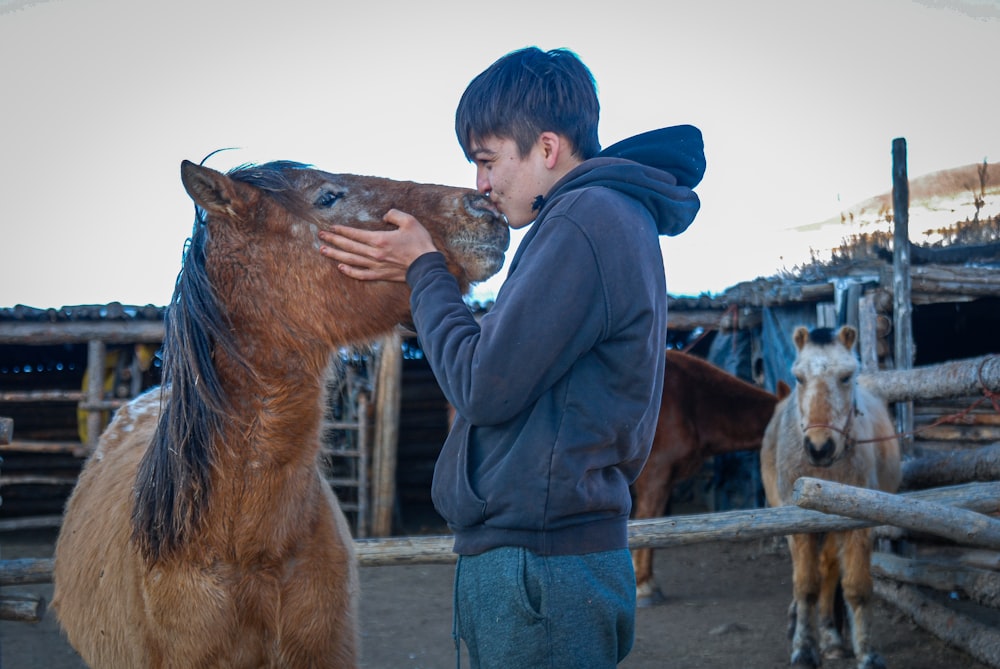 a young boy standing next to a brown horse