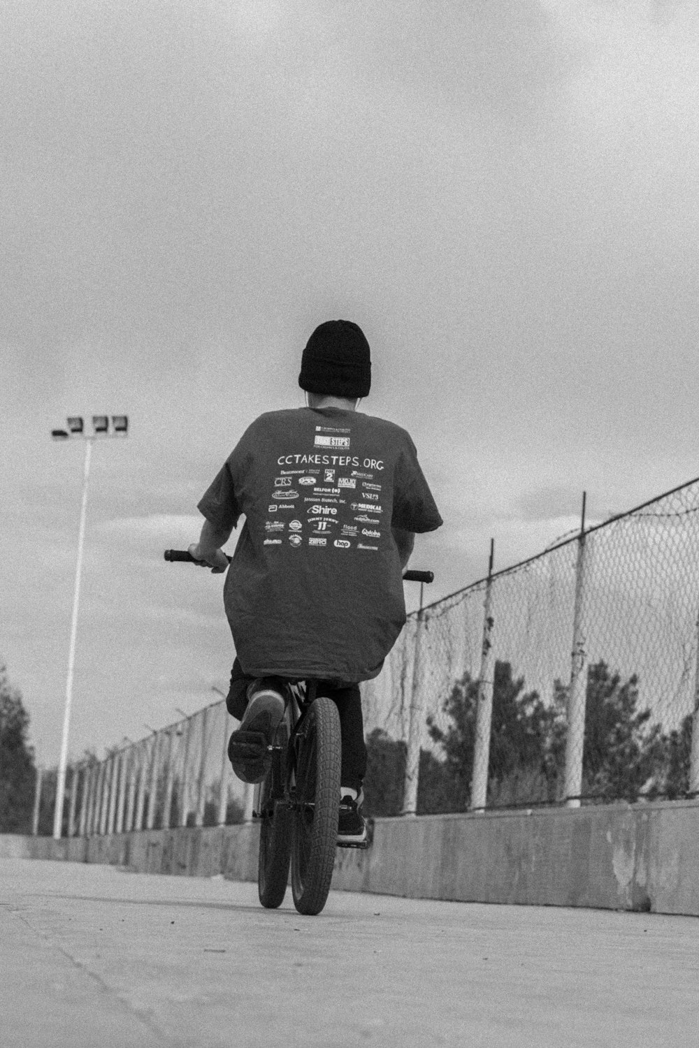 a man riding a bike down a street next to a fence