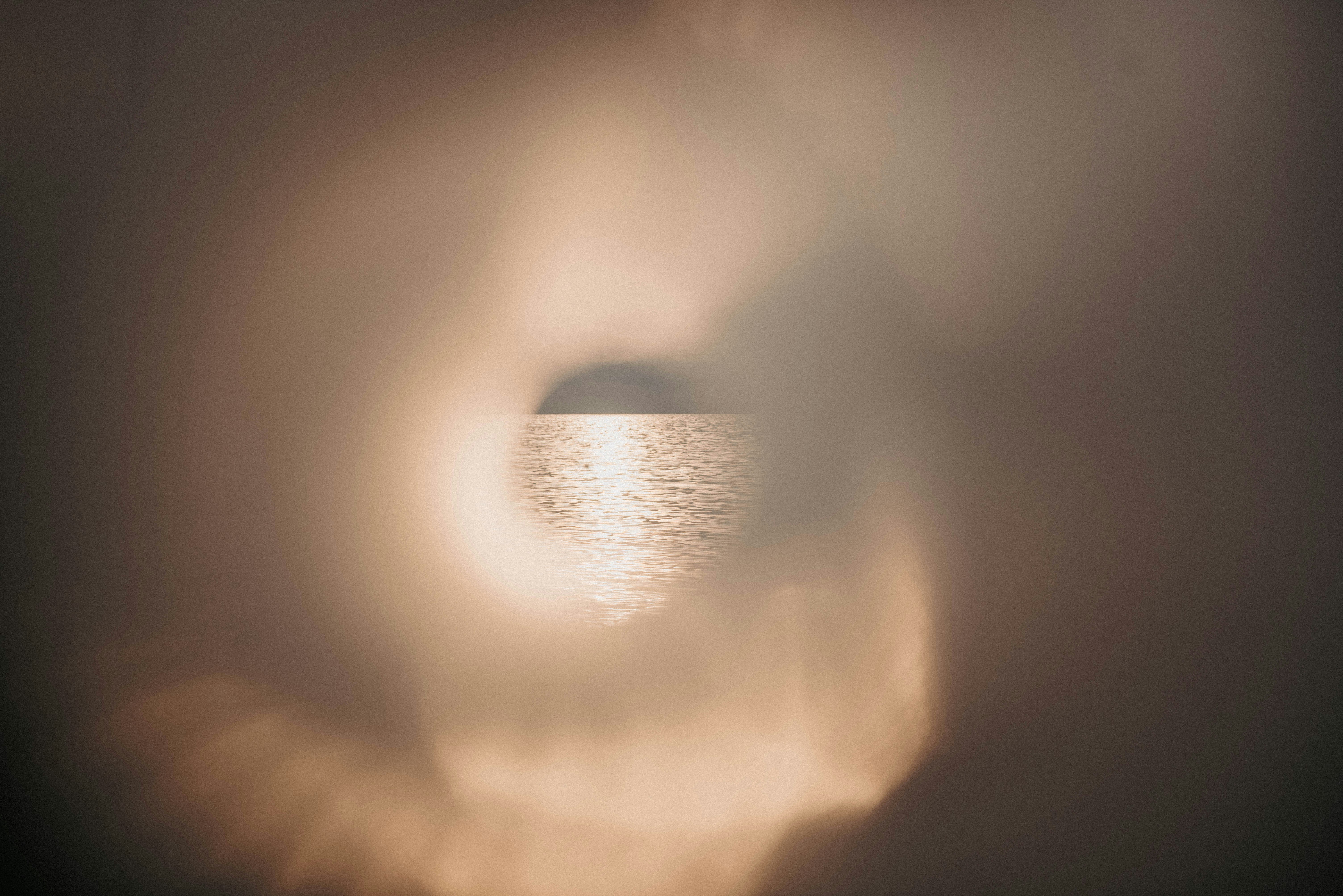 a view of a body of water through a hole in the clouds
