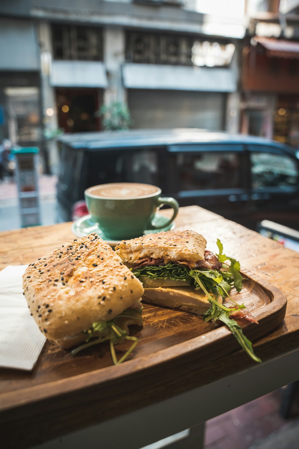 a wooden table topped with a sandwich and a cup of coffee