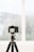 A professional camera is mounted on a tripod indoors, facing a large window with a blurred view of the outside. The camera's display screen shows a focused image, likely a landscape or architectural scene.