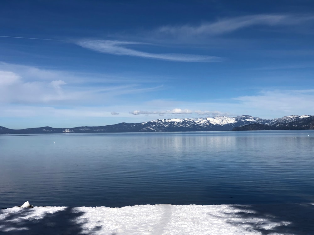 a body of water surrounded by snow covered mountains