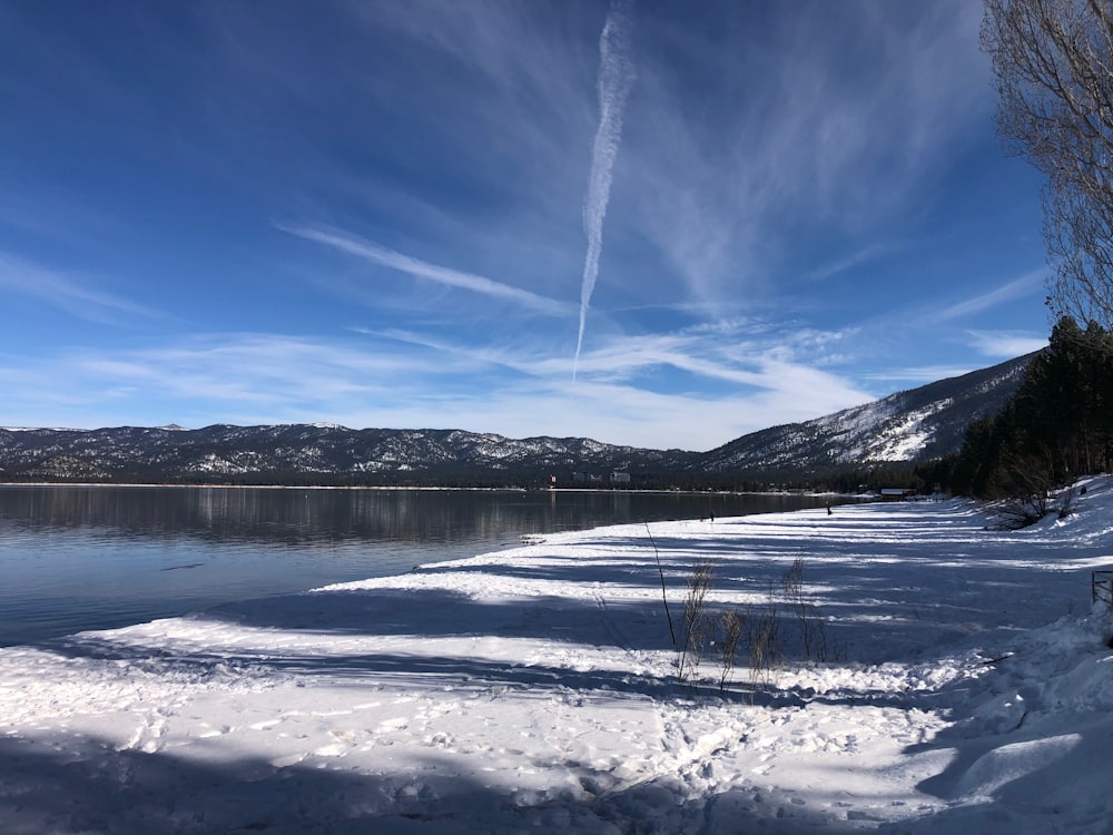 Una larga línea de nieve cubierta de tierra junto a un cuerpo de agua