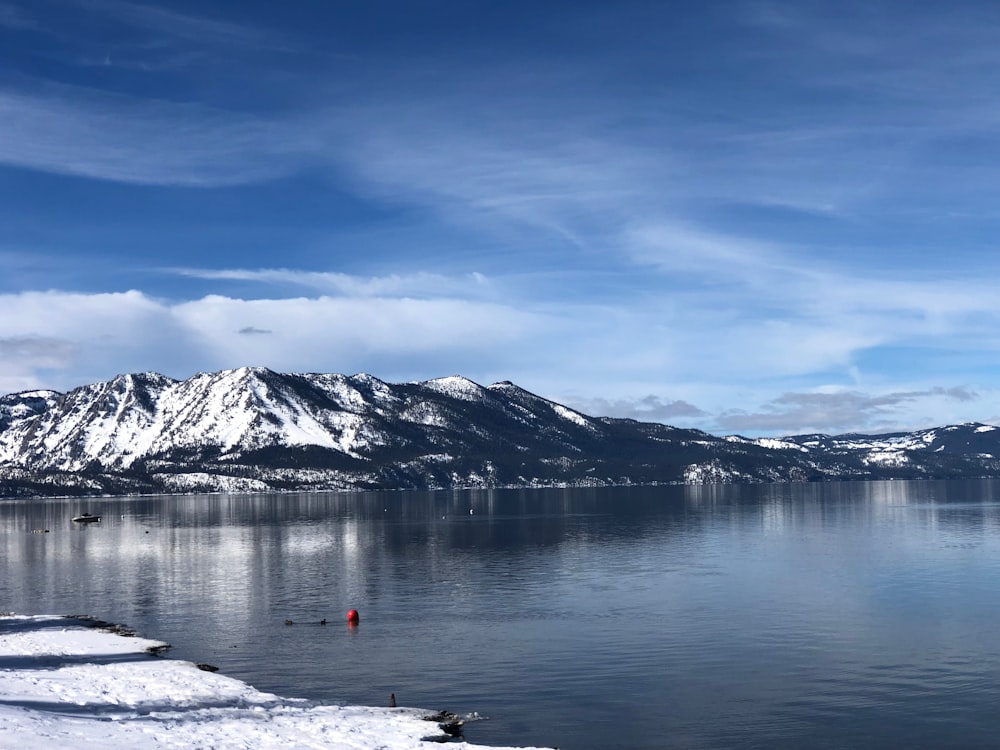 a body of water surrounded by snow covered mountains