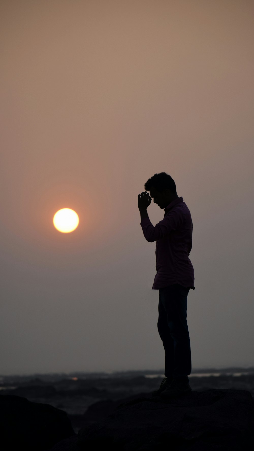 a person standing on top of a rock near the ocean