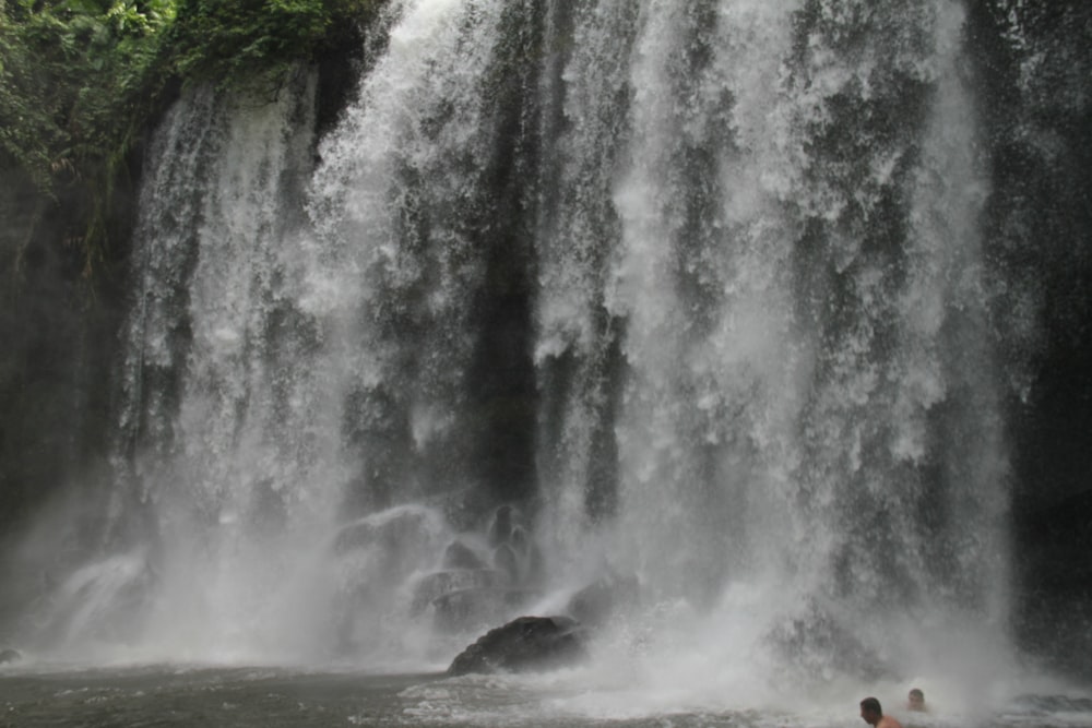 a man standing in front of a waterfall