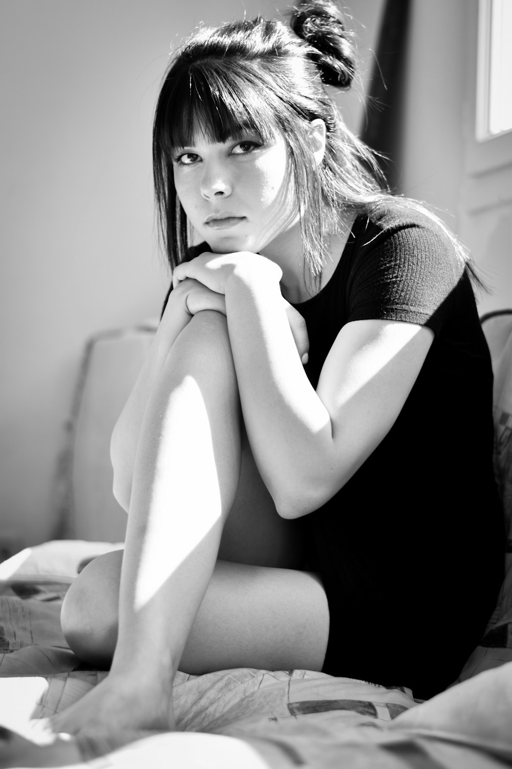 a black and white photo of a woman sitting on a bed