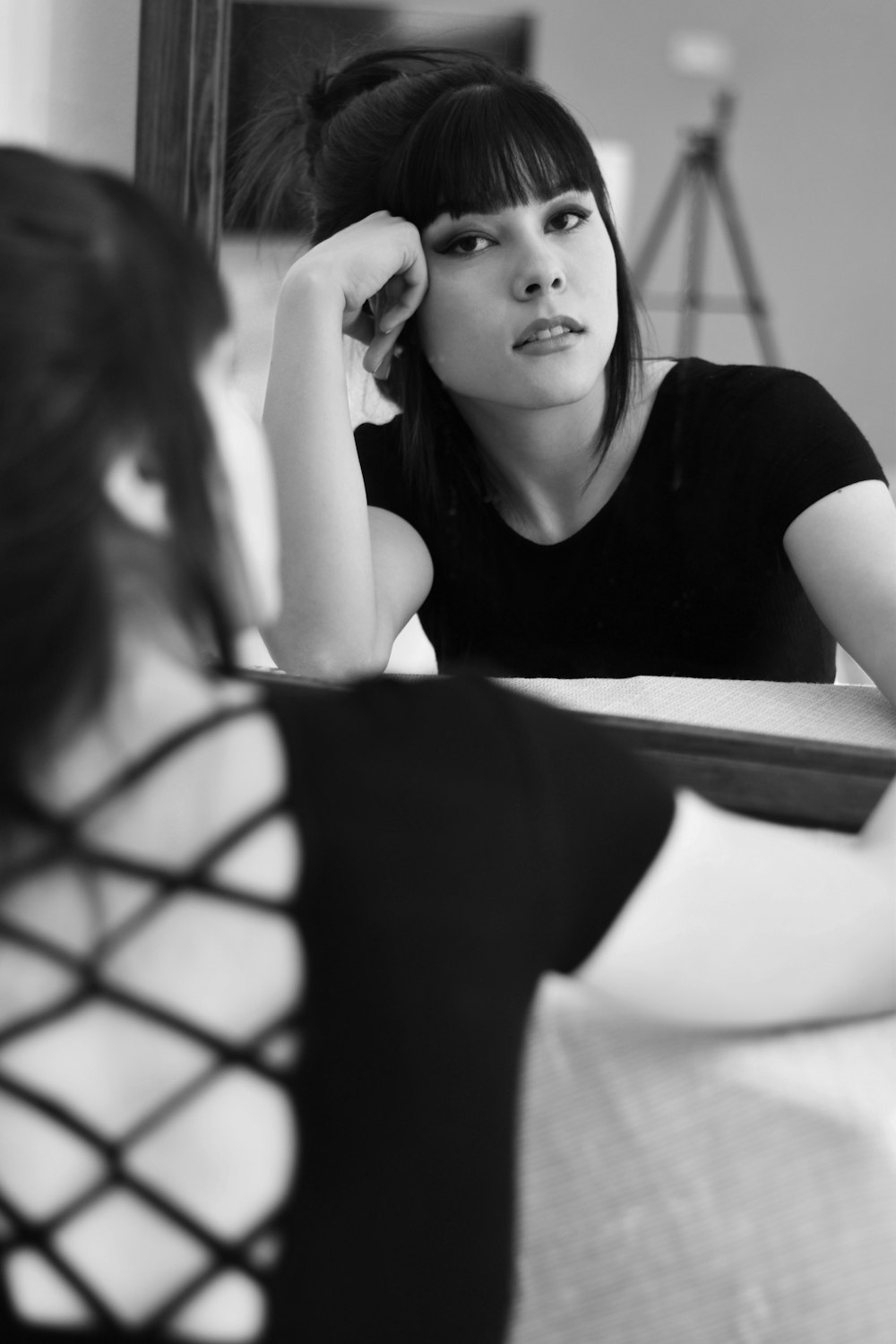 a woman sitting in front of a mirror with her hand on her head