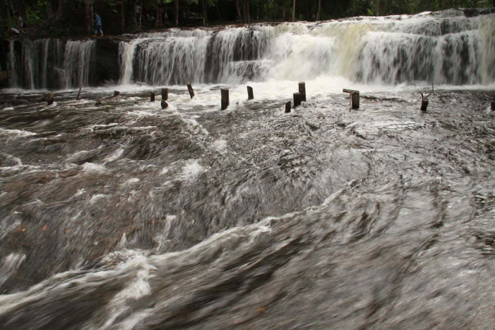 a large waterfall with a bunch of logs sticking out of it