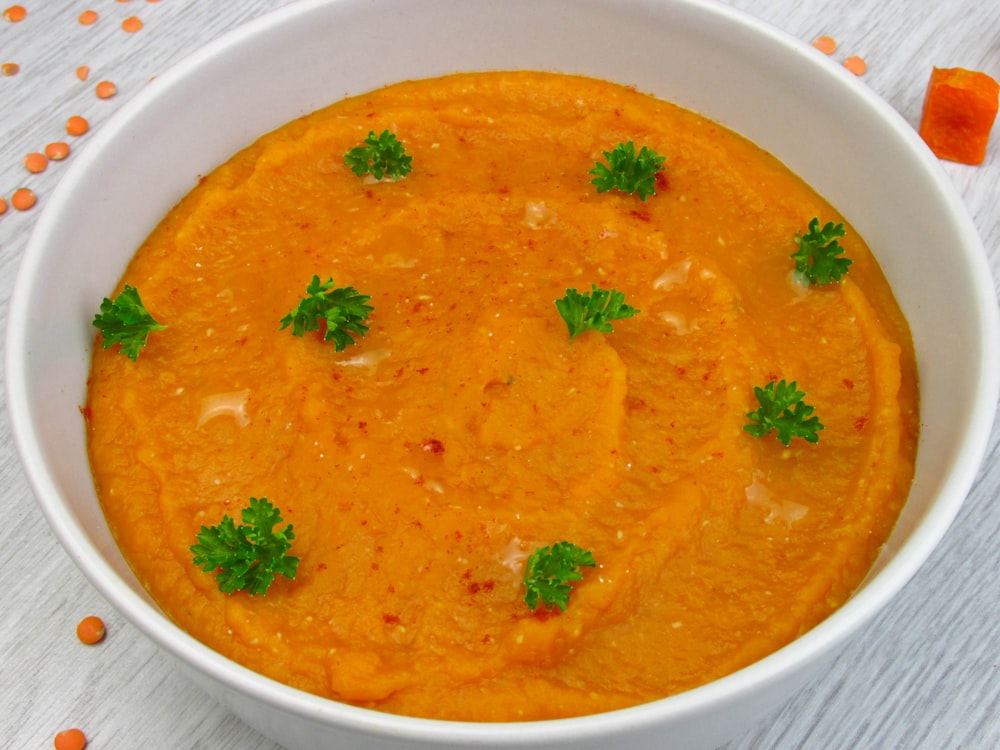 a bowl of carrot soup with parsley on top