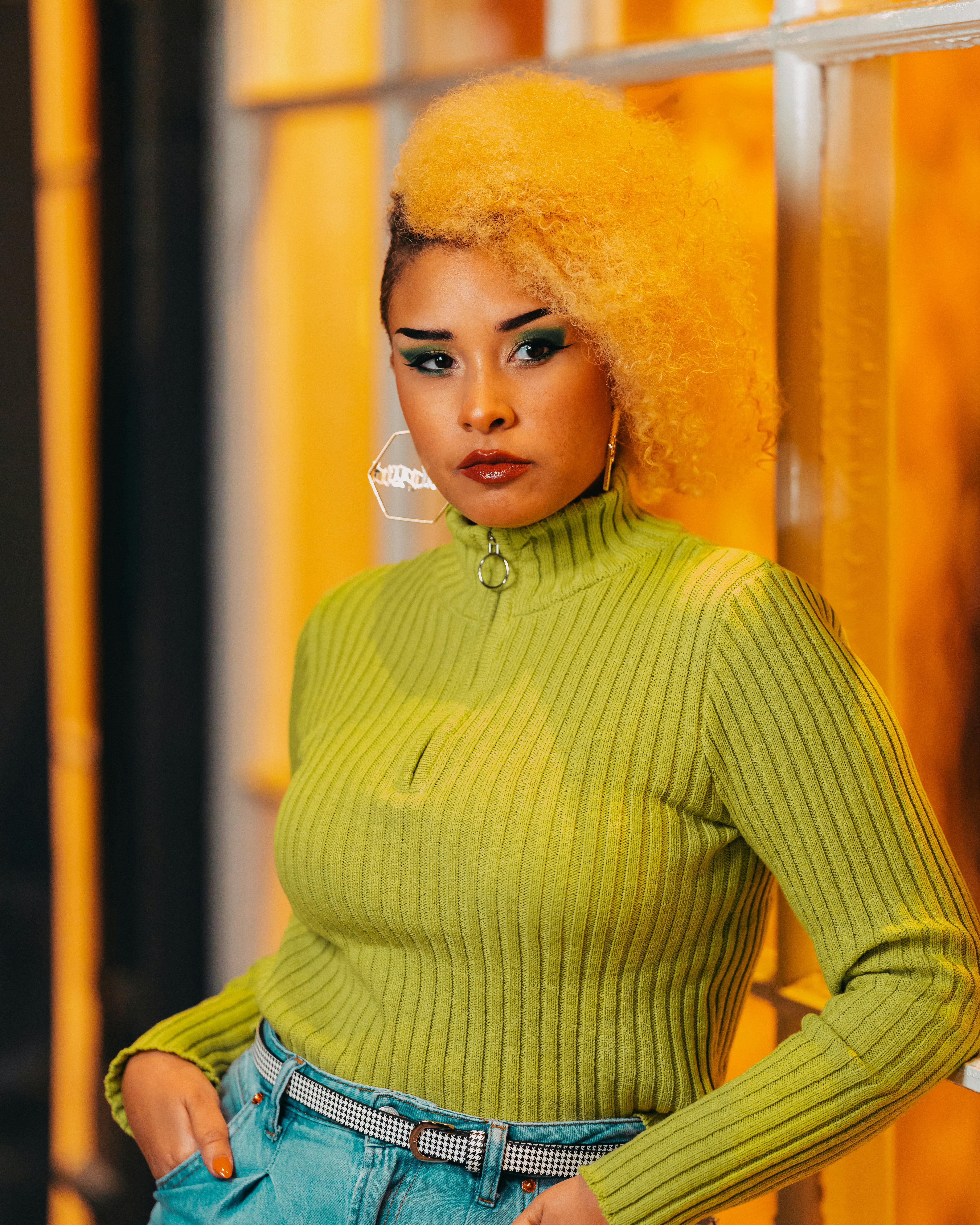 Seorang wanita dengan rambut kuning cerah sedang berpose untuk berfoto