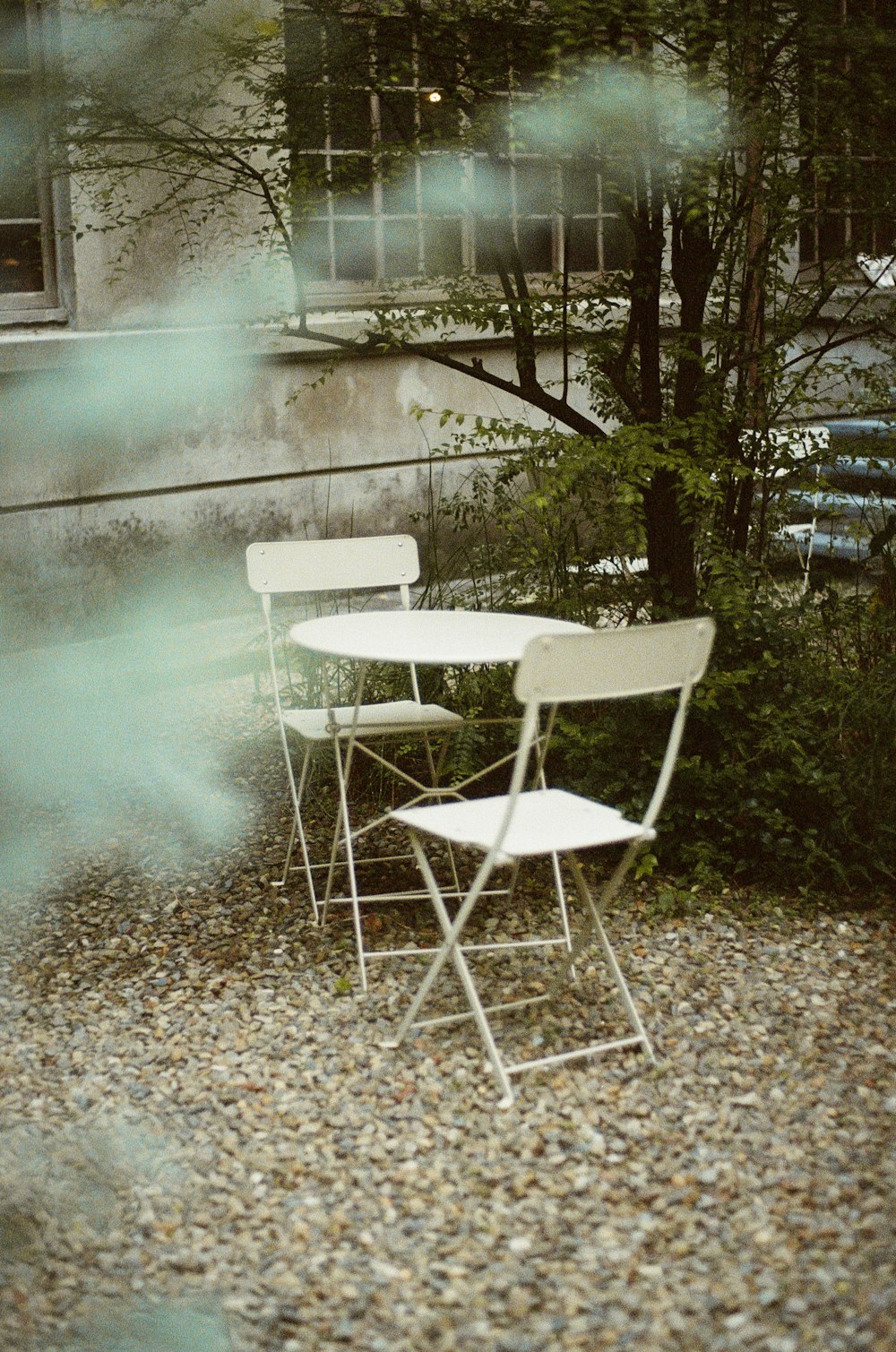 a couple of white chairs sitting on top of a gravel field