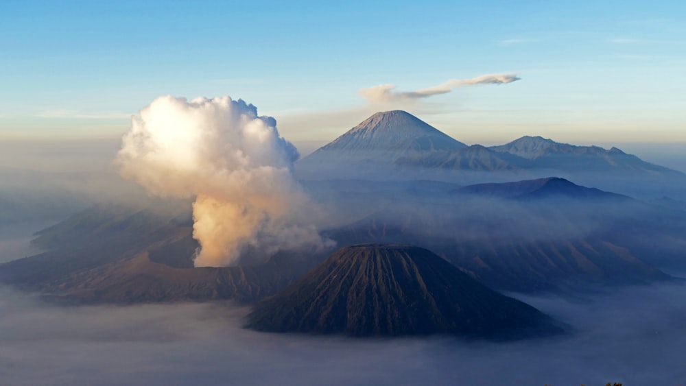 a large cloud of smoke billows from the top of a mountain