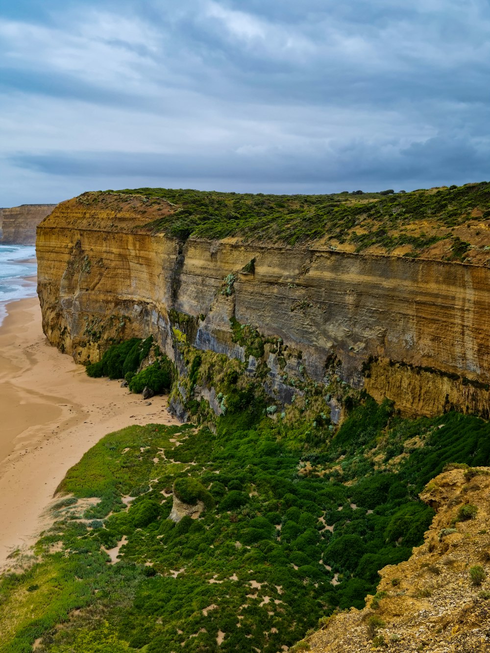 a large cliff on the side of a beach next to the ocean