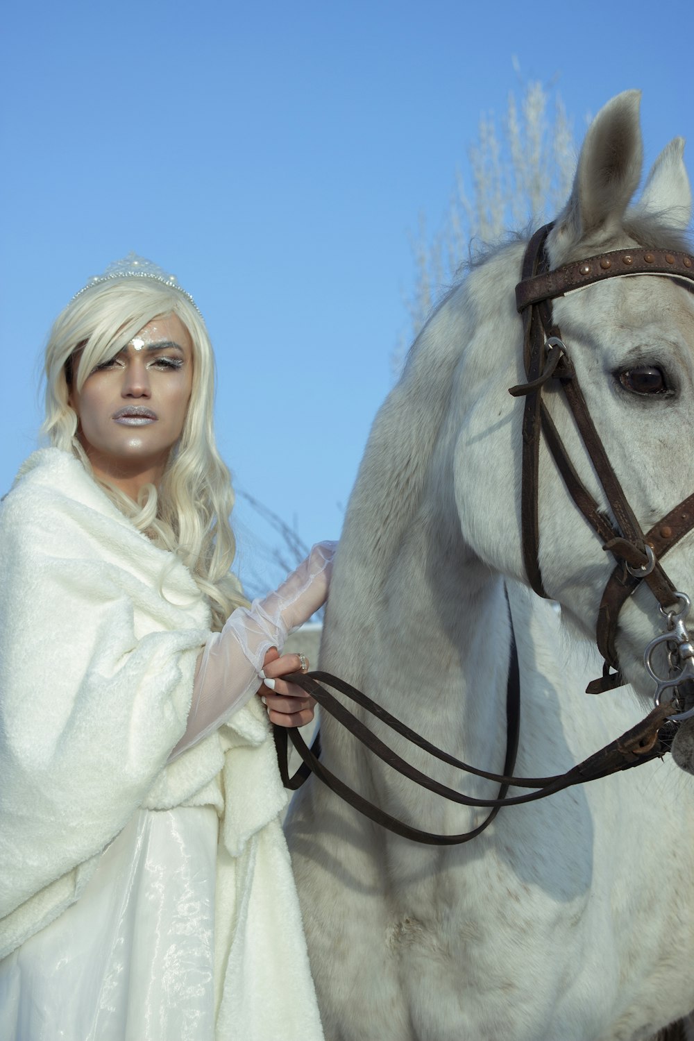 a woman in a white dress standing next to a white horse