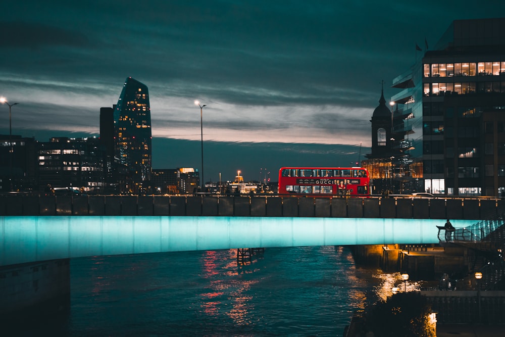 a red double decker bus driving over a bridge