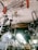 Numerous metallic antennas and fans are hanging from the ceiling of a shop. The items appear to be stacked closely together, creating a cluttered visual effect. There is a signboard partially visible in the background.