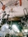Numerous metallic antennas and fans are hanging from the ceiling of a shop. The items appear to be stacked closely together, creating a cluttered visual effect. There is a signboard partially visible in the background.