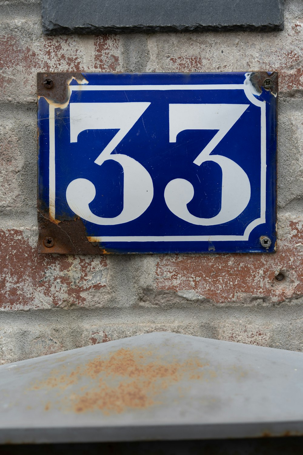 a blue and white sign on a brick wall