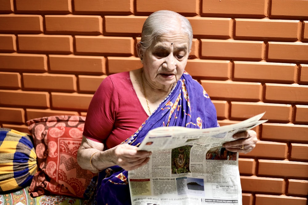 a woman reading a newspaper while sitting on a couch