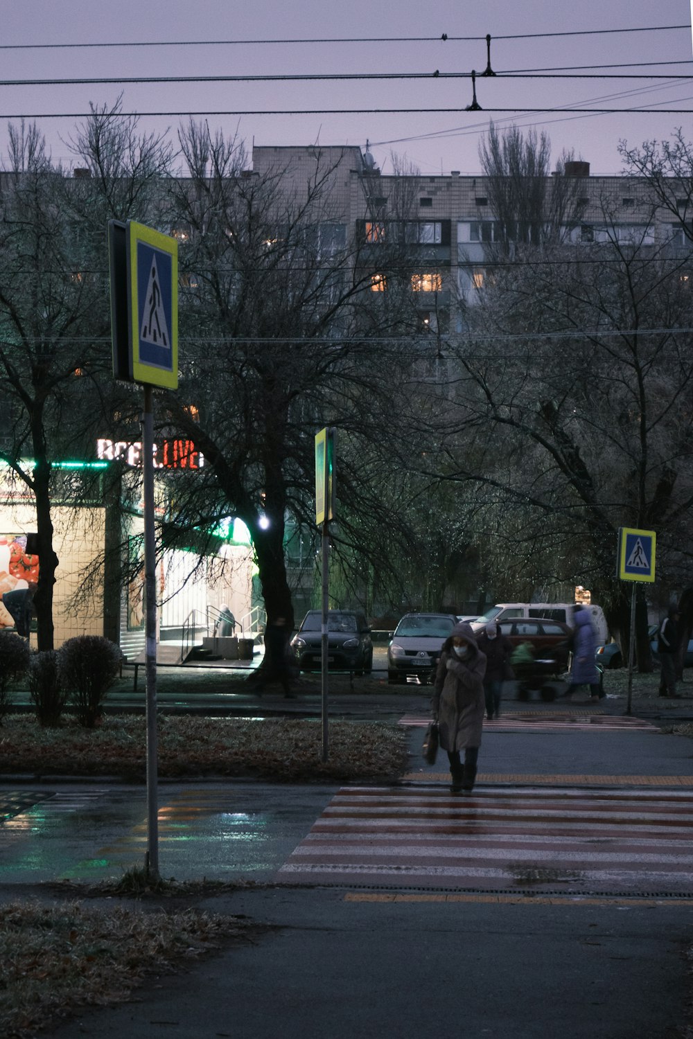 a couple of people crossing a street at night