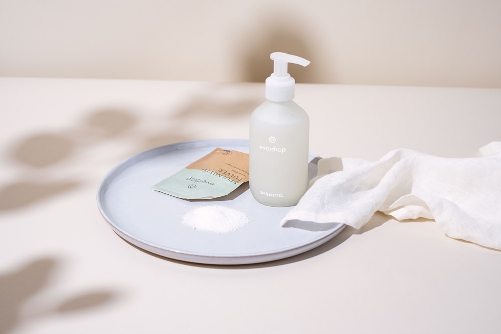 a bottle of lotion sitting on top of a white plate