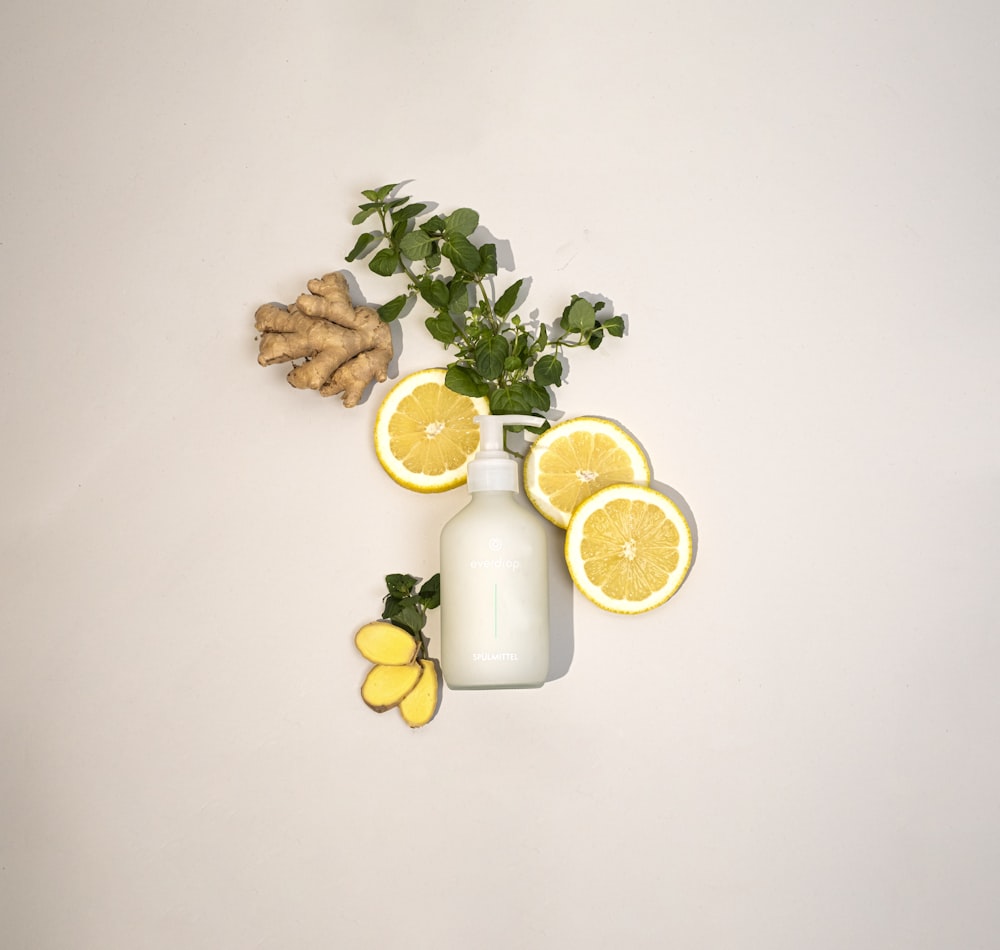 a white vase filled with lemons next to a plant
