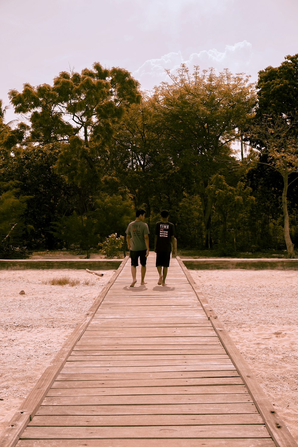긴 나무 산책로를 걷고 있는 두 사람
