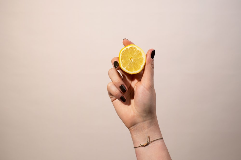 a woman holding a half of a lemon in her hand