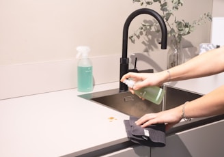 a woman is cleaning a kitchen sink with a rag