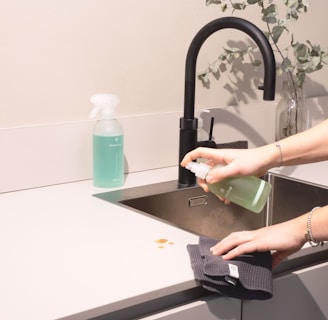 a woman is cleaning a kitchen sink with a rag