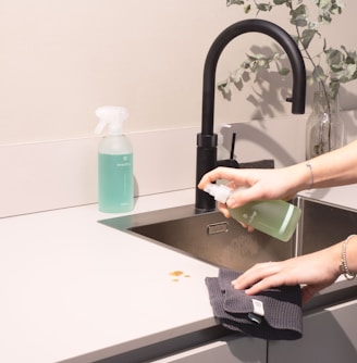 a woman is cleaning a kitchen sink with a rag