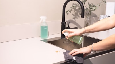 a woman is cleaning a kitchen sink with a rag
