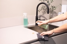 a woman is cleaning a kitchen sink with a rag
