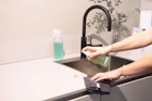 a woman is cleaning a kitchen sink with a rag