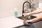 a woman is cleaning a kitchen sink with a rag