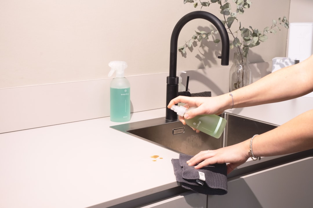 a woman is cleaning a kitchen sink with a rag,