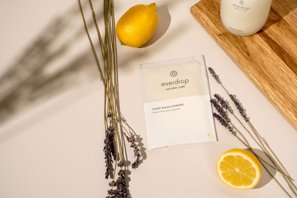 a wooden cutting board topped with a lemon next to a bottle of lotion