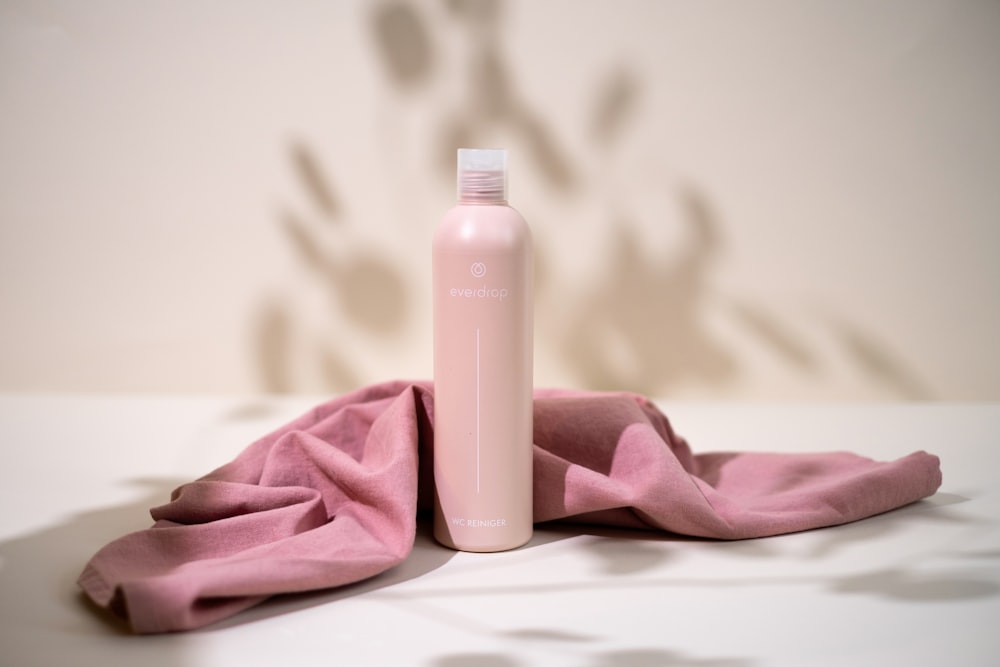 a pink bottle sitting on top of a pink cloth