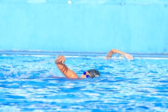 a man swimming in a pool with his arm in the air