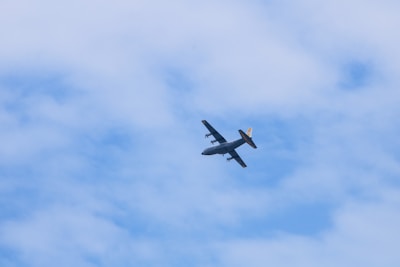 a small airplane flying through a cloudy blue sky