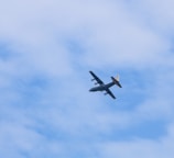 a small airplane flying through a cloudy blue sky