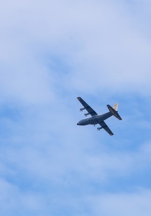 a small airplane flying through a cloudy blue sky