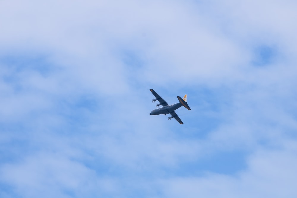 a small airplane flying through a cloudy blue sky