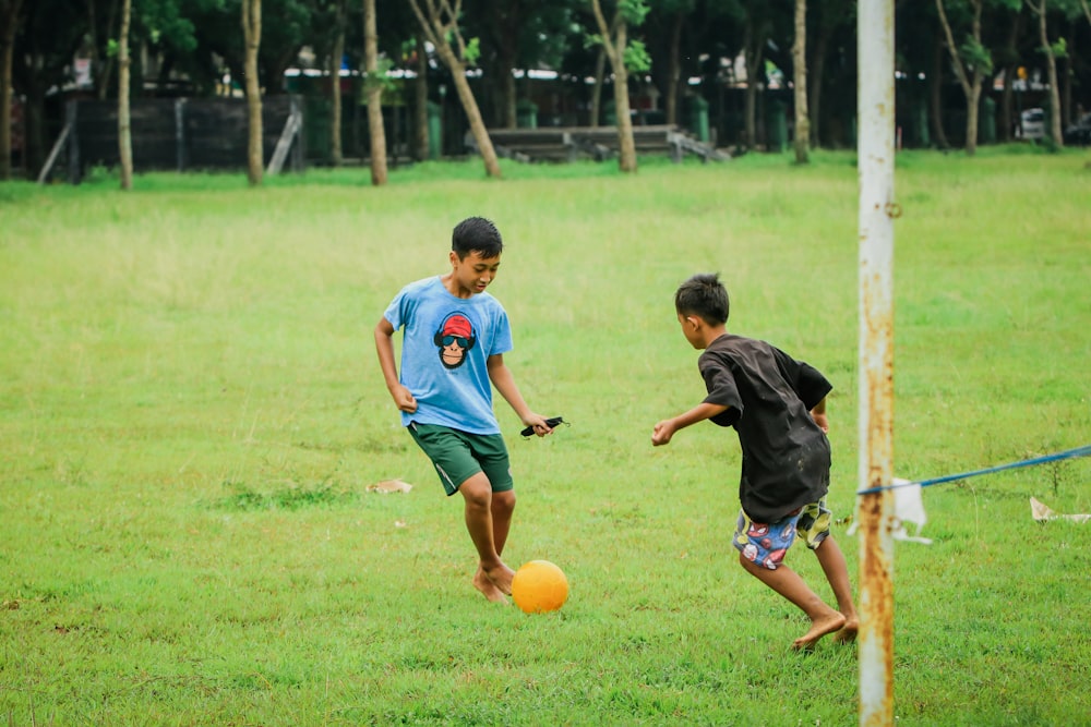 Un par de jóvenes pateando una pelota de fútbol amarilla