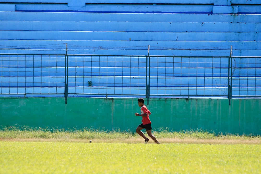 a young man running across a lush green field