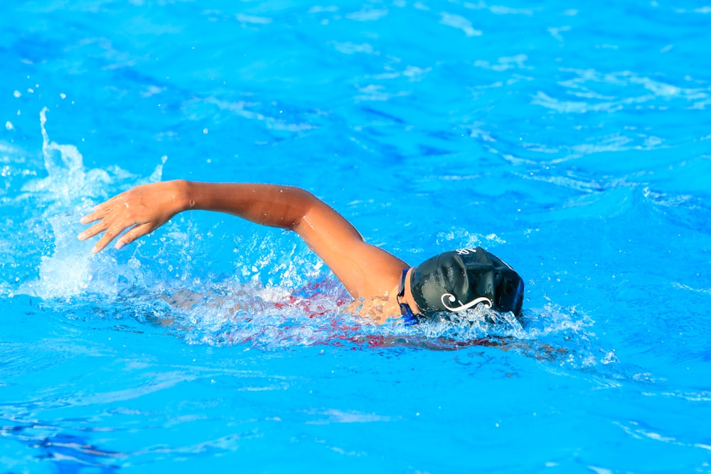 a person swimming in a pool with blue water