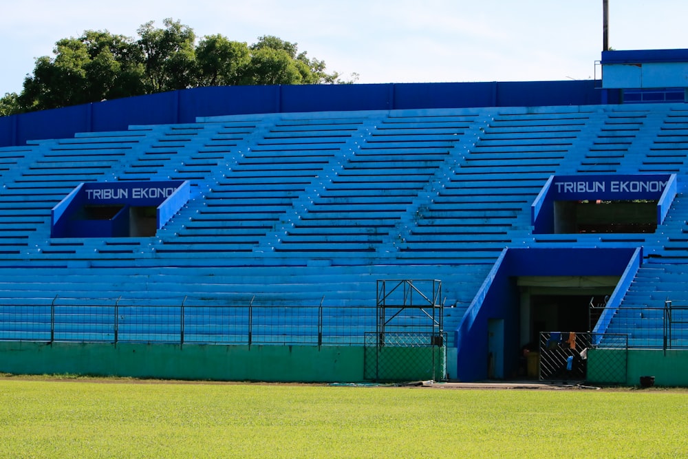 a large blue stadium with a green field in front of it