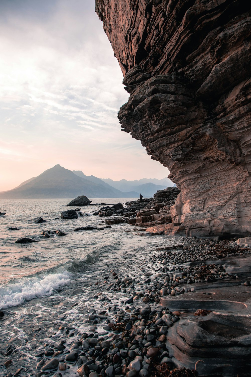 a person standing on a rocky beach next to the ocean